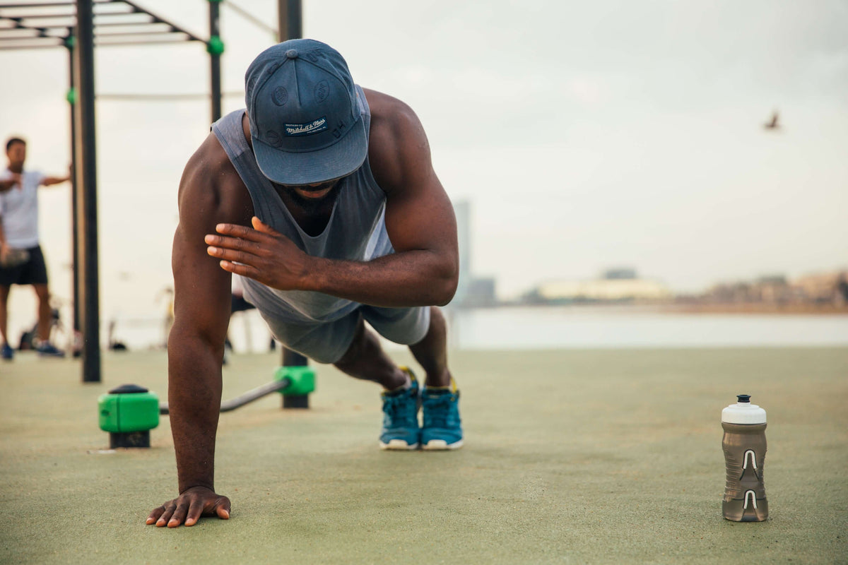 Hombre haciendo flexiones a un brazo al aire libre